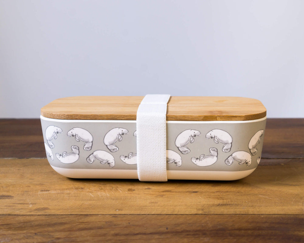 bamboo lunch box with dugong print with wooden lid and white elastic strap to hold lid on 