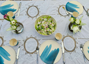 
                  
                    outside table setting with picnic tableware ,bamboo plates and salad bowl with blue wave patterns table layed with white table cloth and  flowers in vases
                  
                