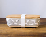 dugong printed lunch box with white elastic strap around  bamboo box and wooden lid
