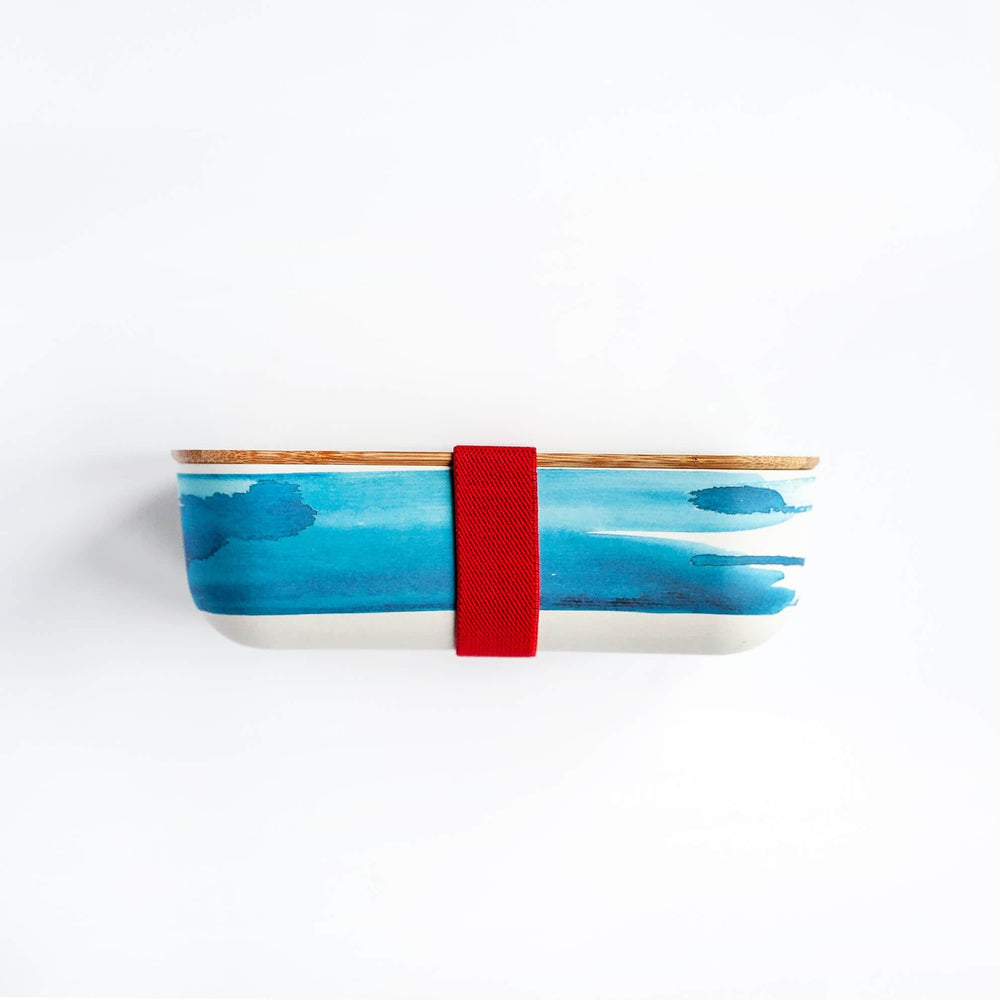 
                  
                    blue wave printed on  bamboo lunch box with wooden lid and red straps
                  
                