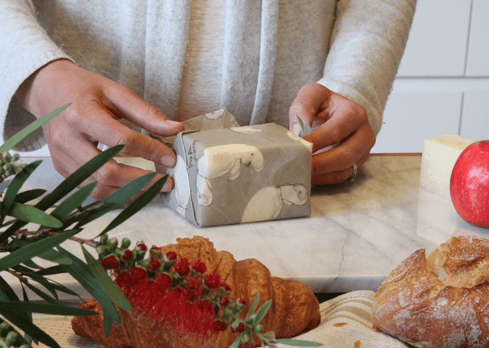 cheese being wrapped in beeswax wrap with dugong print