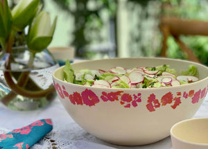 
                  
                    close up of pink coral salad bowl with green salad styled on beautiful out door table
                  
                
